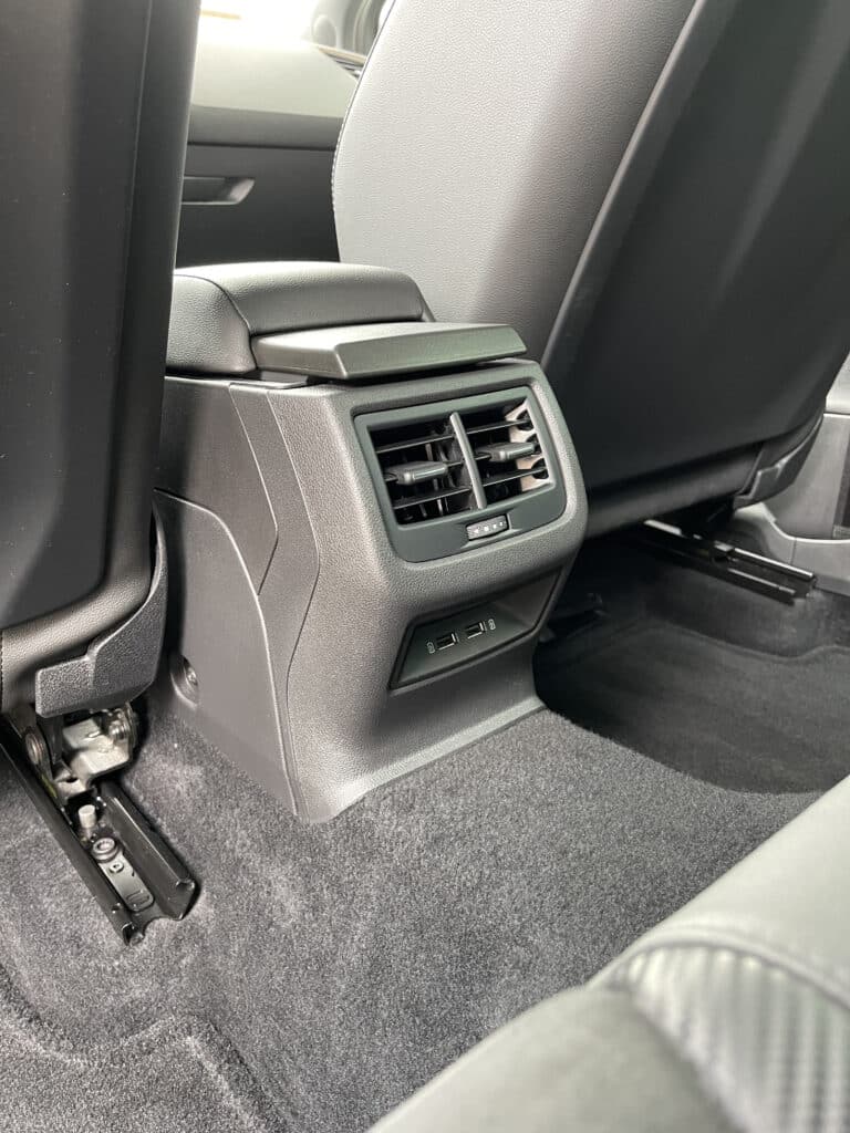 Console centrale arrière: ventilation HVAC et ports USB-C. Intérieur de voiture: console centrale arrière texturée noire, doubles bouches d'aération, contrôle HVAC et deux ports USB-C.